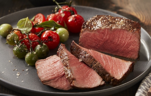 Medium rare steak prepared with roasted tomatoes