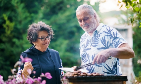 Man and woman grilling meat together outdoors