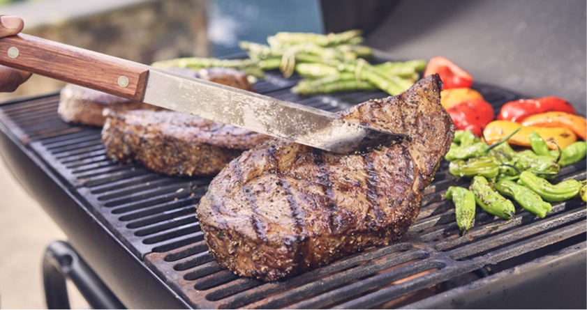 Preparing steaks on the grill with peppers